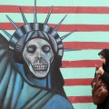 An Iranian woman walks past an anti-US&nbsp;m